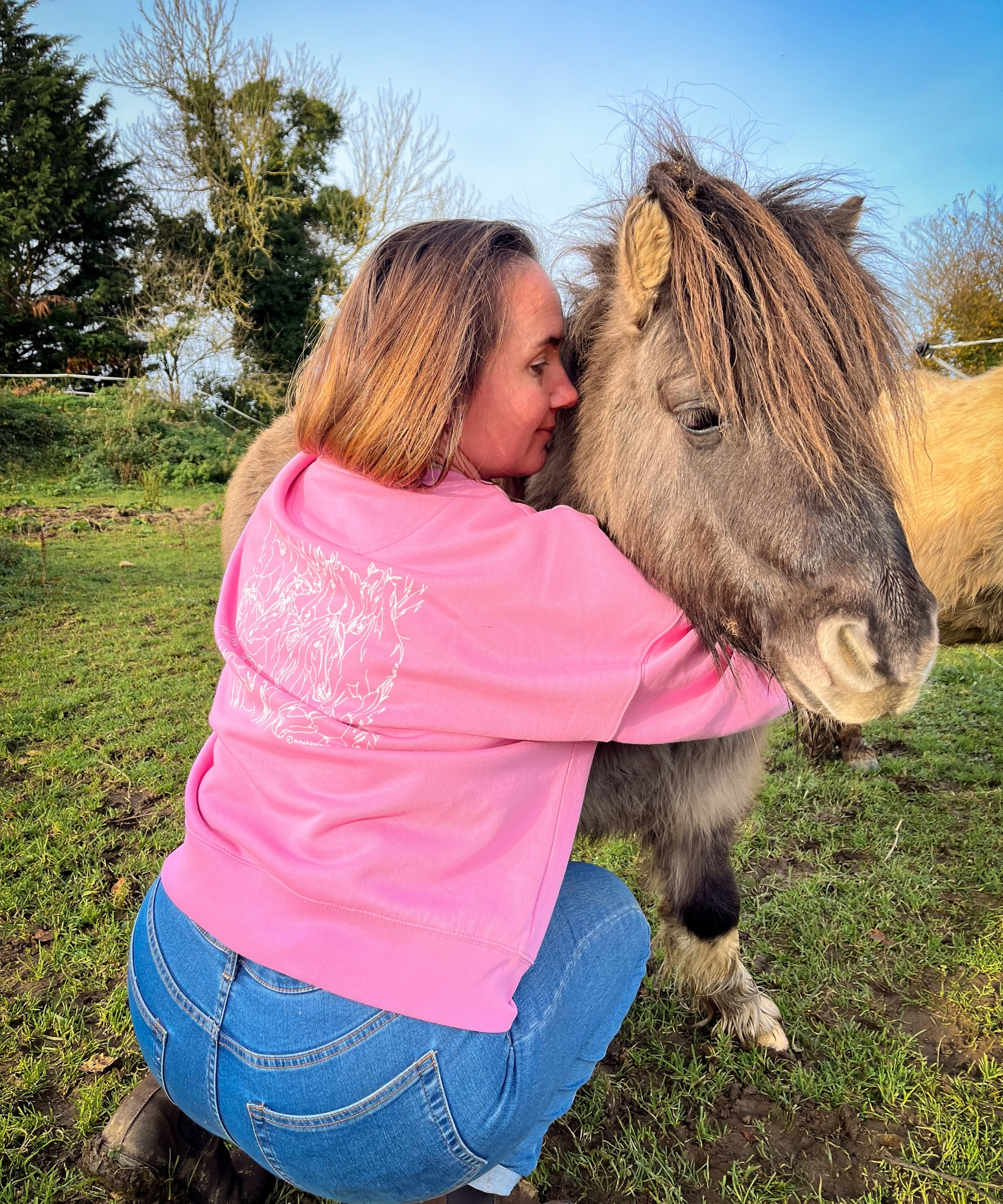 cavalière portant un pull équestre rose en coton bio avec une illustration de chevaux câline son shetland pie